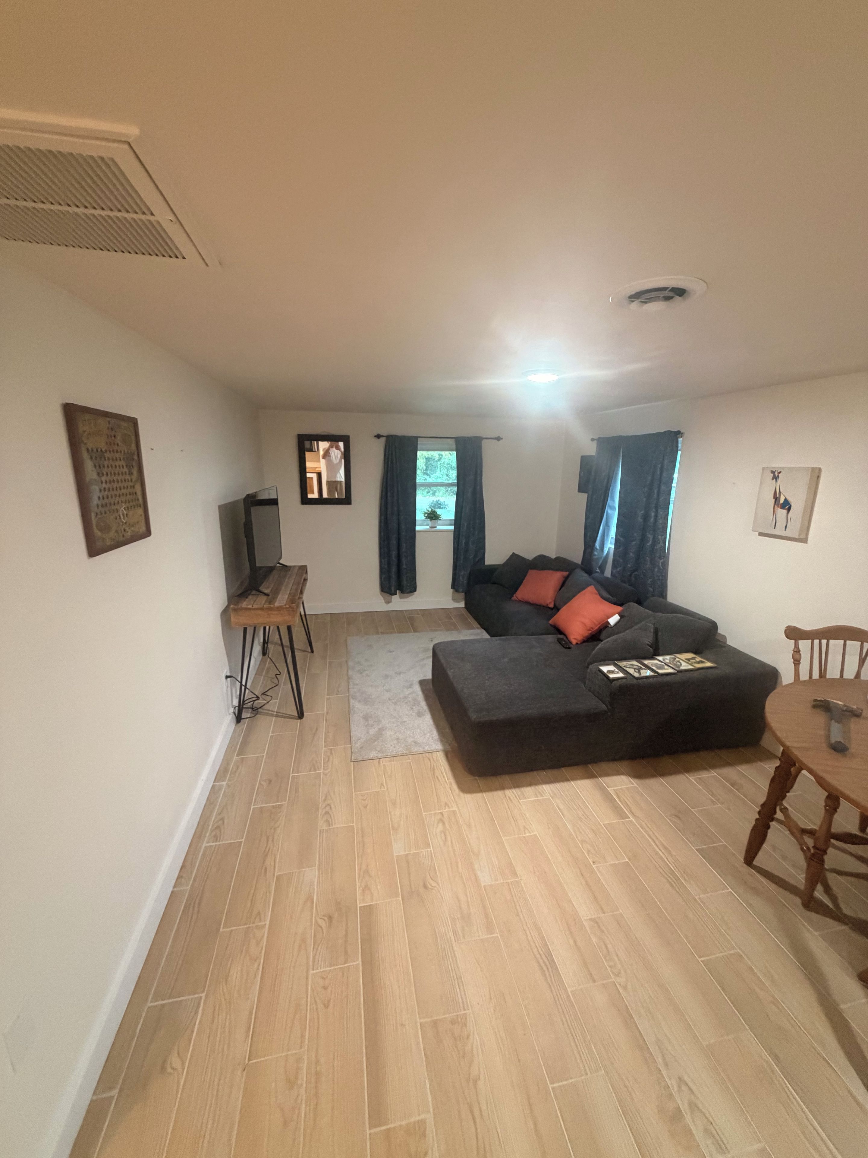 A living room with a sofa, a coffee table, a dining table, and a small side table.