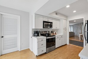 A modern kitchen with white cabinetry, a built-in microwave, a coffee maker, and a stainless steel oven. - 3-Minute walk to beach, Screen porch, Seabrook Island Retreat - 751 Spinnaker (Seabrook Island)