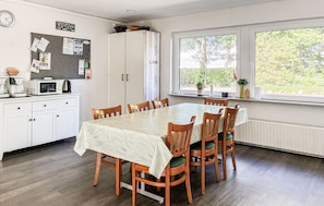 A dining area with a table set for six, wooden chairs, a white cabinet with a clock, and a bulletin board on the wall. - Nice home in ølgod with WiFi (Ølgod)