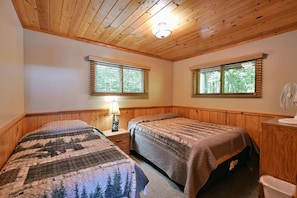 A room with two beds, wooden walls, a ceiling fan, and windows with blinds. - Year-Round Trail Access | Cozy Cabin on Lake (Cable)
