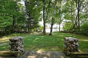 A stone bench with a wooden platform in a park with trees and a lake in the background. - Year-Round Trail Access | Cozy Cabin on Lake (Cable)