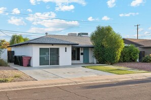 A residential house with a garage, a small porch, and a well-maintained lawn. - Scottsdale Retreat Home w/ Pool and Patio (Scottsdale)