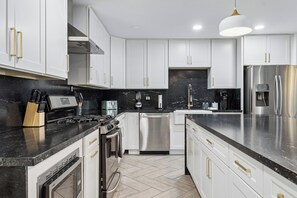 A modern kitchen with white cabinets, stainless steel appliances, and a black countertop. - Scottsdale Retreat Home w/ Pool and Patio (Scottsdale)
