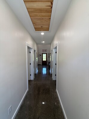 A hallway with white walls, a polished floor, and a wooden ceiling. - Cozy 2-bedroom cottage #2 in peaceful Tuscumbia with AC (Tuscumbia)