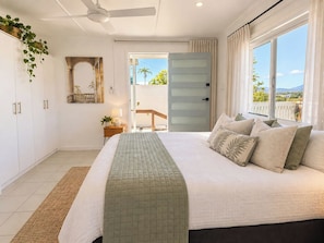 A bedroom with a bed, a ceiling fan, a window with curtains, and a view of the outdoors. - Hillside Vista| West End Retreat w/Panoramic Views (West End)