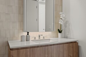 A modern bathroom with a white sink, wooden vanity, and a potted orchid. - Pearl Coast' One Acre Rooftop Pool Gym Sauna Walk To Santa Monica Beach and Pier (Santa Monica)
