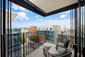A balcony with a view of the cityscape, featuring modern buildings and a clear sky.