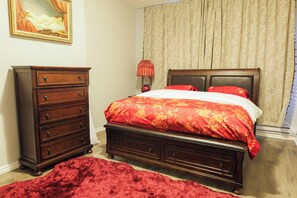 A bedroom with a wooden bed, a dresser, a red rug, and a painting on the wall. - Downtown Toronto 4BR, 2.5 Bath – Prime Queen & Spadina Location (Toronto)