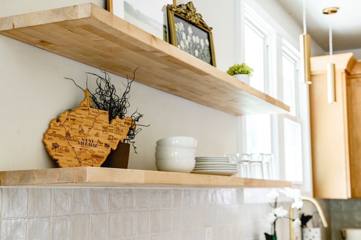 A kitchen with a wooden shelf, a decorative vase, and a framed picture.