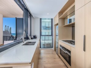 Eine moderne Küche mit einer großen Kochinsel, einem eingebauten Ofen und Blick ins Freie.