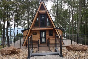 Eine Holzhütte mit einem Satteldach, einer Holzdar Terrasse und einem Metallgeländer.