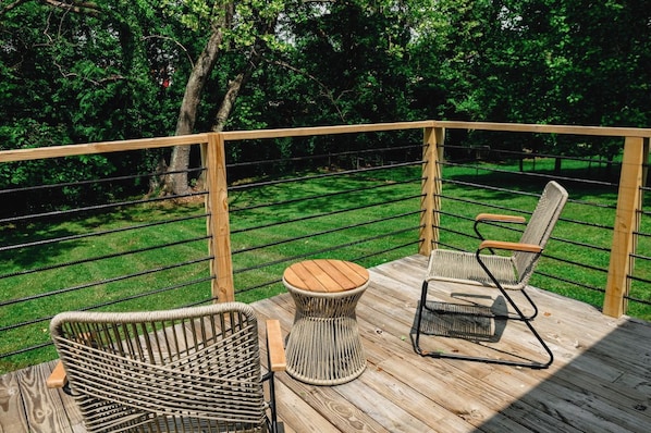A wooden deck with wicker furniture and a view of a grassy area.