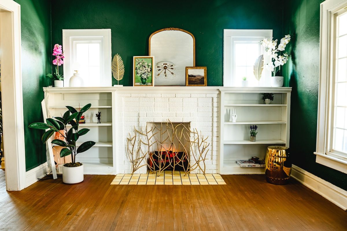 A room with a white fireplace, green walls, and wooden flooring.