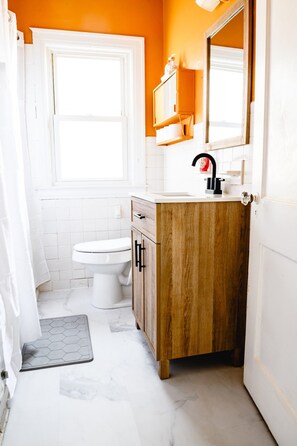 Et badeværelse med toilet, trækommode og et vindue.