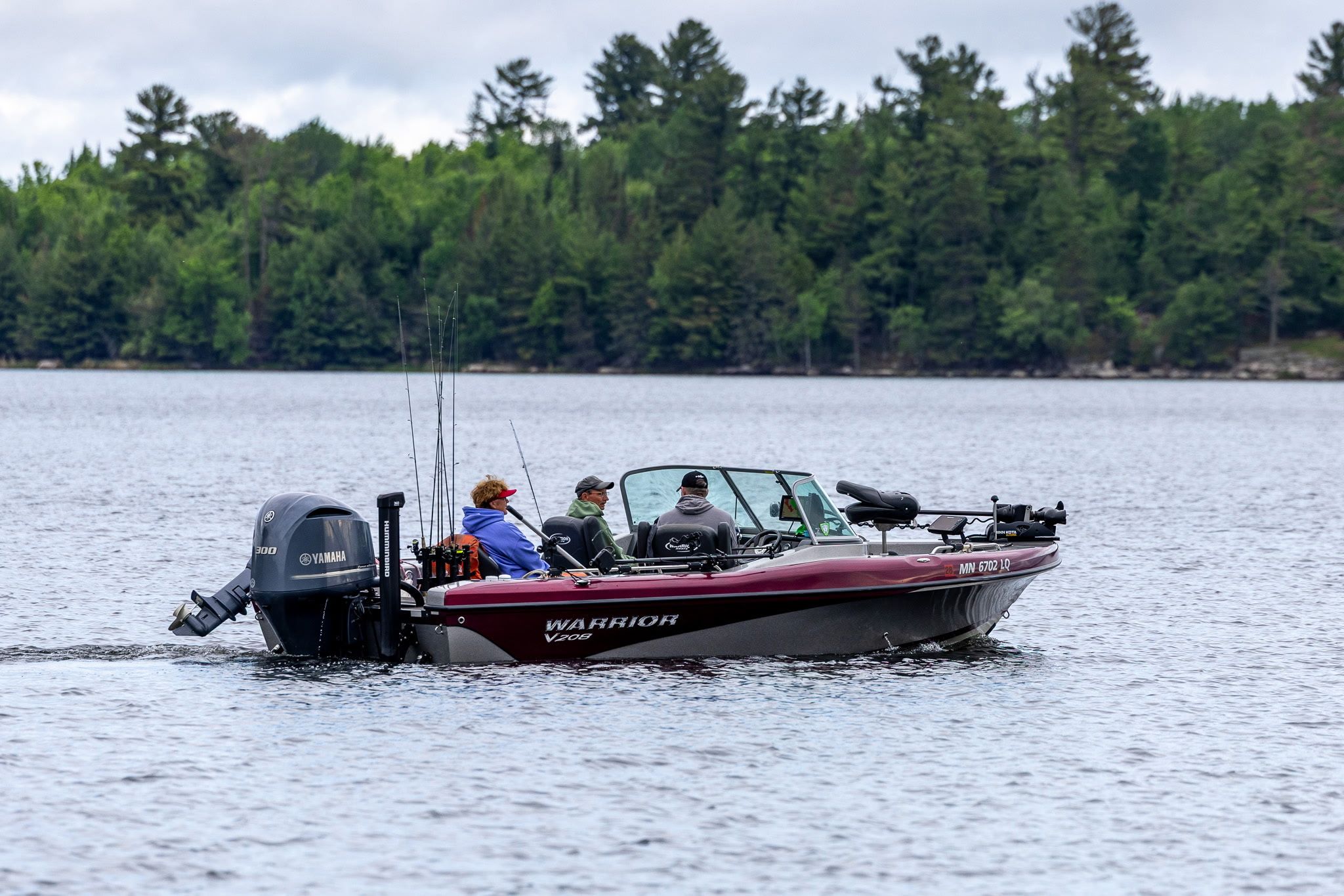 A boat with a Yamaha outboard motor, a person wearing a red cap, and another in a blue jacket.