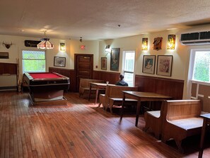 Une salle de billard équipée d’une table de billard, de chaises en bois et d’œuvres d’art accrochées aux murs.