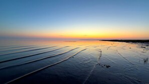 En strand med rolige vand og en bro i det fjerne.