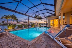 A pool area with lounge chairs and a covered patio. - Gulf-Access Fun, Pool Days & Waterfront Adventures Await - Villa Vitamin Sea - Roelens (Cape Coral)