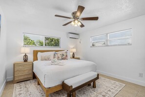 A bedroom with a bed, bedside tables, a ceiling fan, and windows with blinds. - Poolside Fun, Pickleball & Coastal Adventures Await in Fort Myers - Jefferson Palms III - Roelens (Fort Myers Beach)