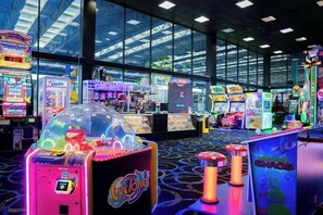 An indoor arcade with various gaming machines, a large glass window, and a ceiling with a grid pattern. - Coco Key Hotel 2 Double Studio Water Park Arcade (Orlando)