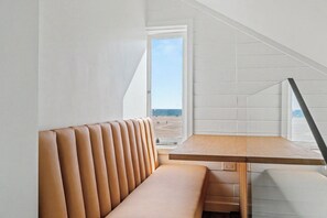 A modern interior with a bench and table, a view of the beach, and a sloped ceiling. - Newly Built On the Beach Studio Loft with Views (Santa Monica)
