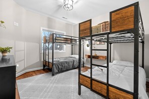 Habitación con literas, un escritorio y una planta.
