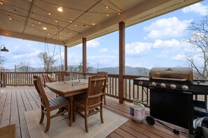 Eine Terrassenausstattung im Freien mit Holztisch und -stühlen, einem Grill und einer Gasflasche.