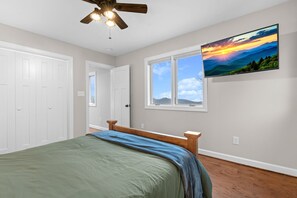 Ein Schlafzimmer mit einem Bett, einem Deckenventilator, einem Fenster mit Blick und einem Bild an der Wand.