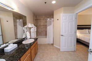 Une salle de bain équipée d’un lavabo, d’un miroir, d’une douche et d’une porte donnant sur une chambre.