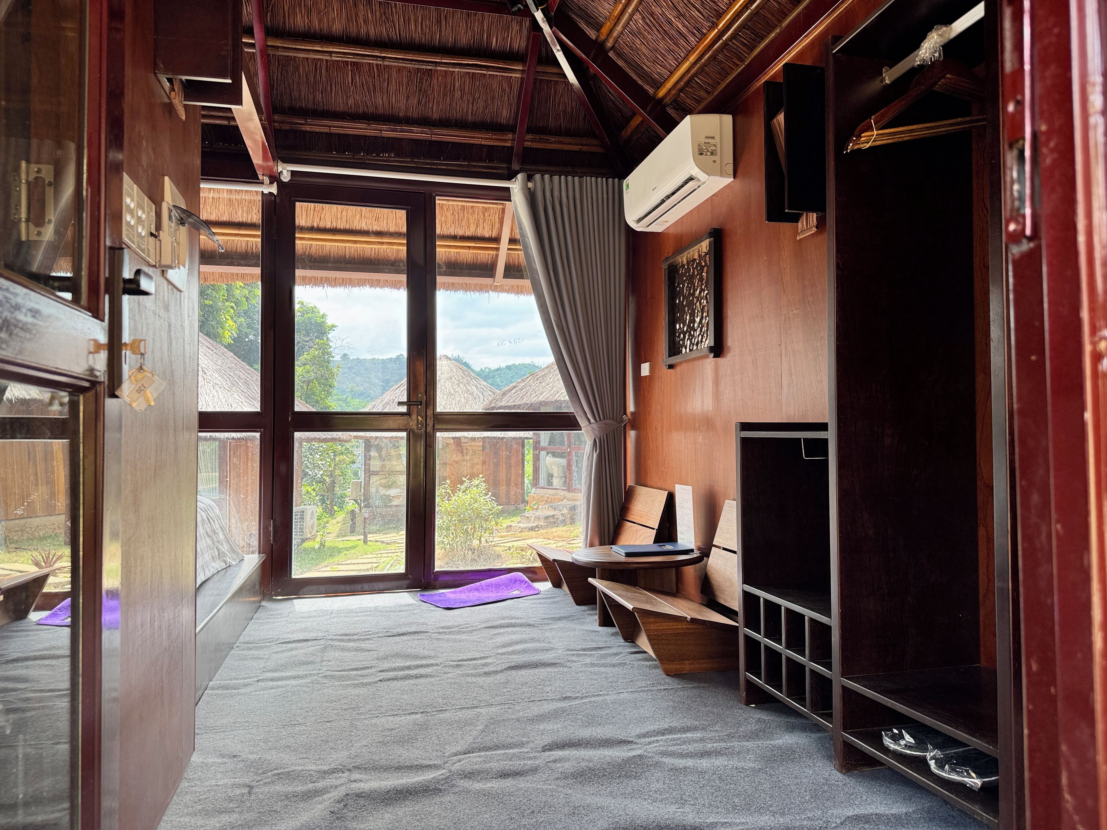 Een kamer met een groot raam, een bed, een bureau en een kledingkast.