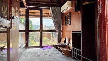 Een kamer met een groot raam, een bed, een bureau en een kledingkast.