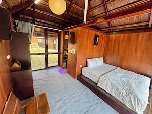 Een kamer met een bed, een bureau, een stoel, een raam en een plafondventilator.