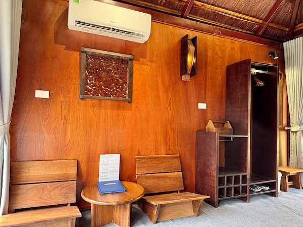 A wooden room with a built-in bench, a small table, an air conditioning unit, and a wardrobe.
