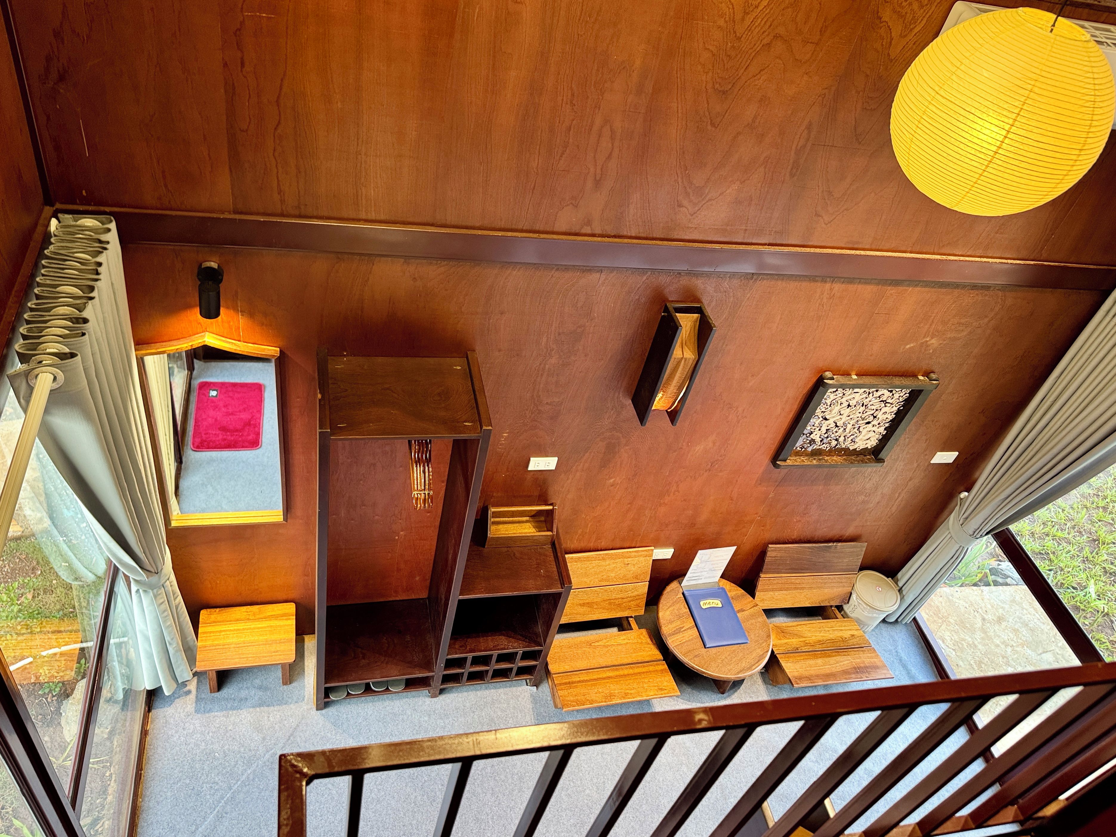 Un intérieur en bois avec un escalier, une petite table avec un menu et une fenêtre avec des rideaux.