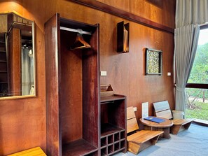 A room with a wooden wardrobe, a mirror, a wooden bench, and a small table with a book. - JOYSTAY - Ra Village (Cat Hai)