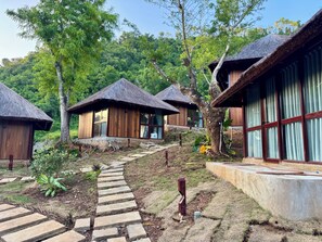 A resort with thatched-roof cottages, a stone pathway, and lush greenery.