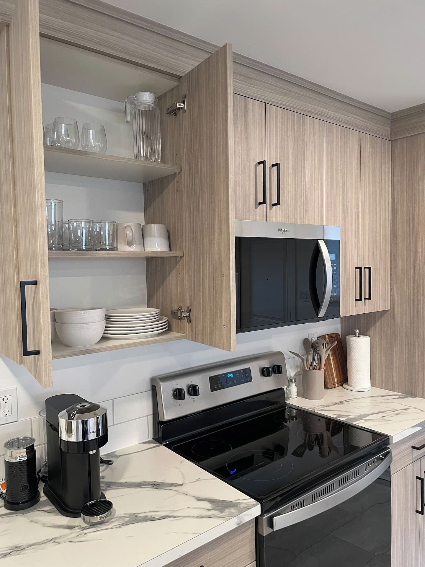 A modern kitchen with a built-in microwave, oven, and espresso machine.