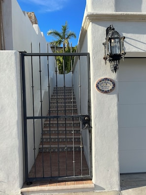 A gated entrance with a tiled staircase leading to a white building, a decorative lantern, and a sign with a message. - Wonderful 2-bedroom house with AC in San José del Cabo (San José del Cabo)