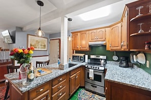 A kitchen with granite countertops, wooden cabinets, a stainless steel stove, and a microwave. - Carriage House in the trees, Historic St. Augustine (St. Augustine)