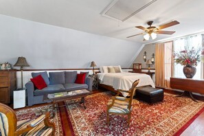 A bedroom with a bed, a sofa, a chair, a desk, and a window with curtains. - Carriage House in the trees, Historic St. Augustine (St. Augustine)