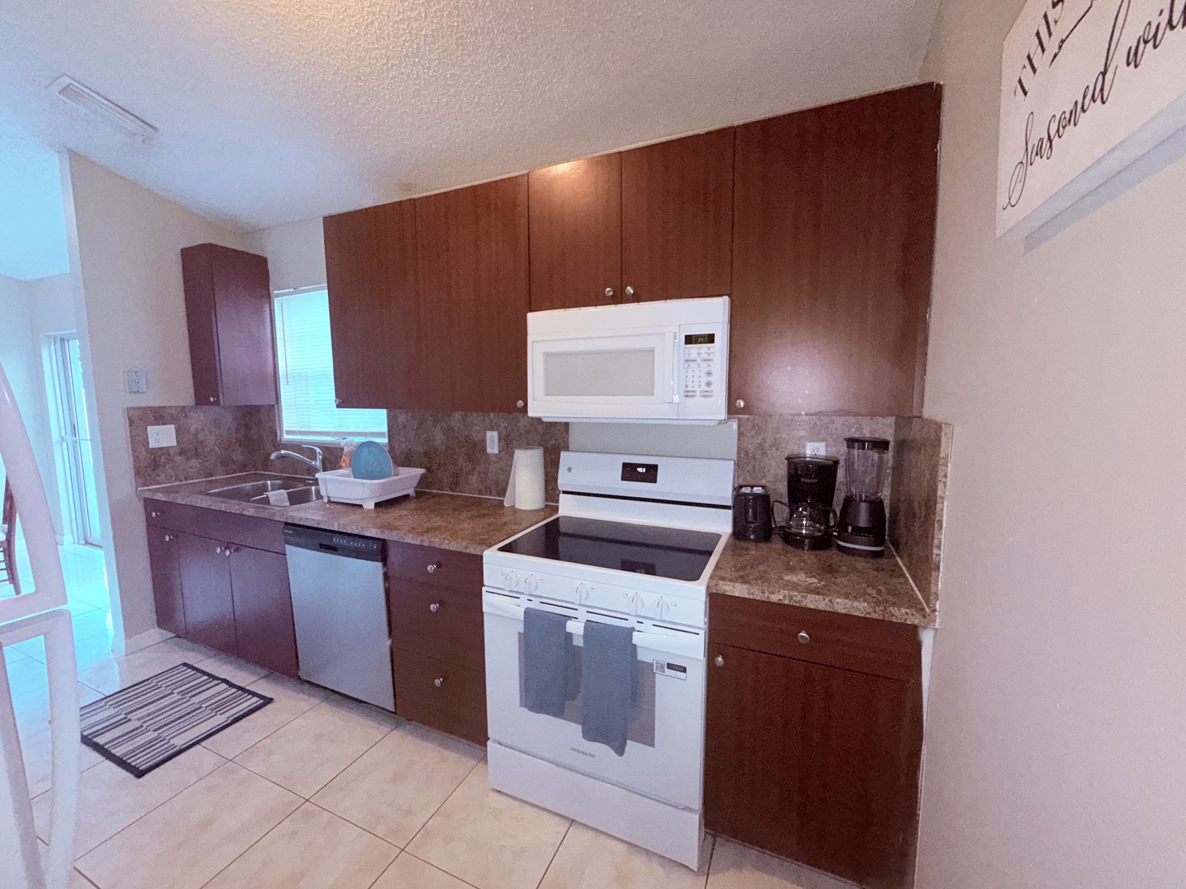 A modern kitchen with wooden cabinets, a microwave, a stove, and a coffee maker.