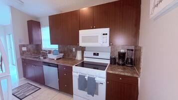 A modern kitchen with wooden cabinets, a microwave, a stove, and a coffee maker.