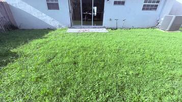 A house with a grassy yard, a sliding glass door, and a small porch.
