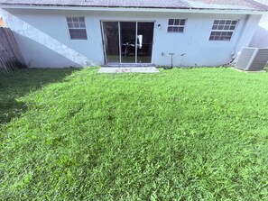 A house with a grassy yard, a sliding glass door, and a small porch.