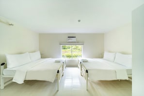 A room with two beds, a window with a view of greenery, and an air conditioning unit on the wall. - The Crib Clark (Mabalacat City)