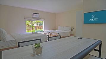 Een kamer met twee enkele bedden, een klein tafeltje met een plant en een raam met uitzicht op groen.