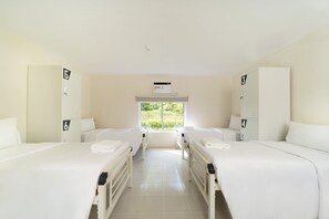 A hotel room with two beds, a window with a view of greenery, and a wall-mounted air conditioning unit. - The Crib Clark (Mabalacat City)