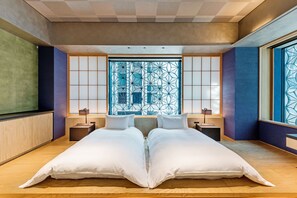 Ett modernt hotellrum med en stor säng, två sängbord och ett stort fönster med ett geometriskt mönster.