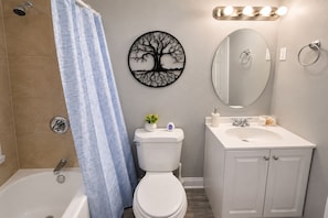 A bathroom with a bathtub, toilet, sink, and a mirror.