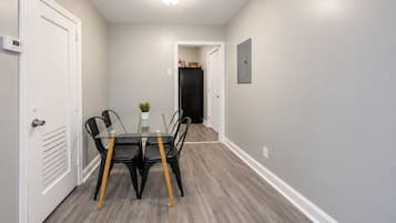 A hallway with a glass-top table and chairs, a potted plant, and a door leading to a closet.